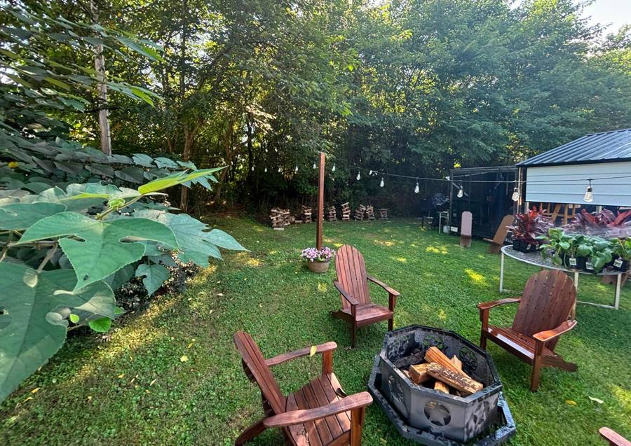 Adirondack chairs around a fire pit in the yard behind the kitchen